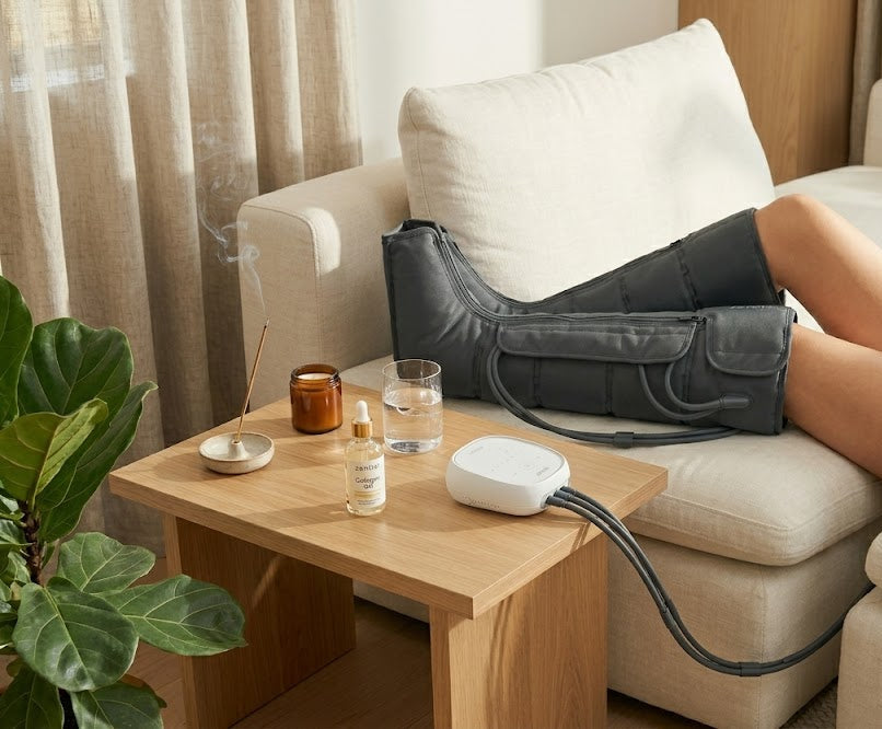 Person using a leg massager on a couch with a coffee table in the foreground